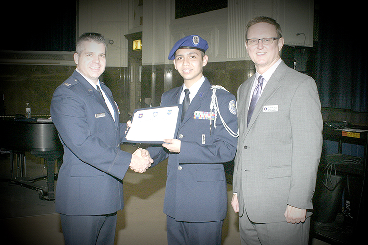 From left to right: Colonel Woods, National AFJROTC Director, presents the “Top Performer” award during the unit evaluation to Cadet Captain Pardey, from Colombia; and Mr. Barron, Regional Director. 